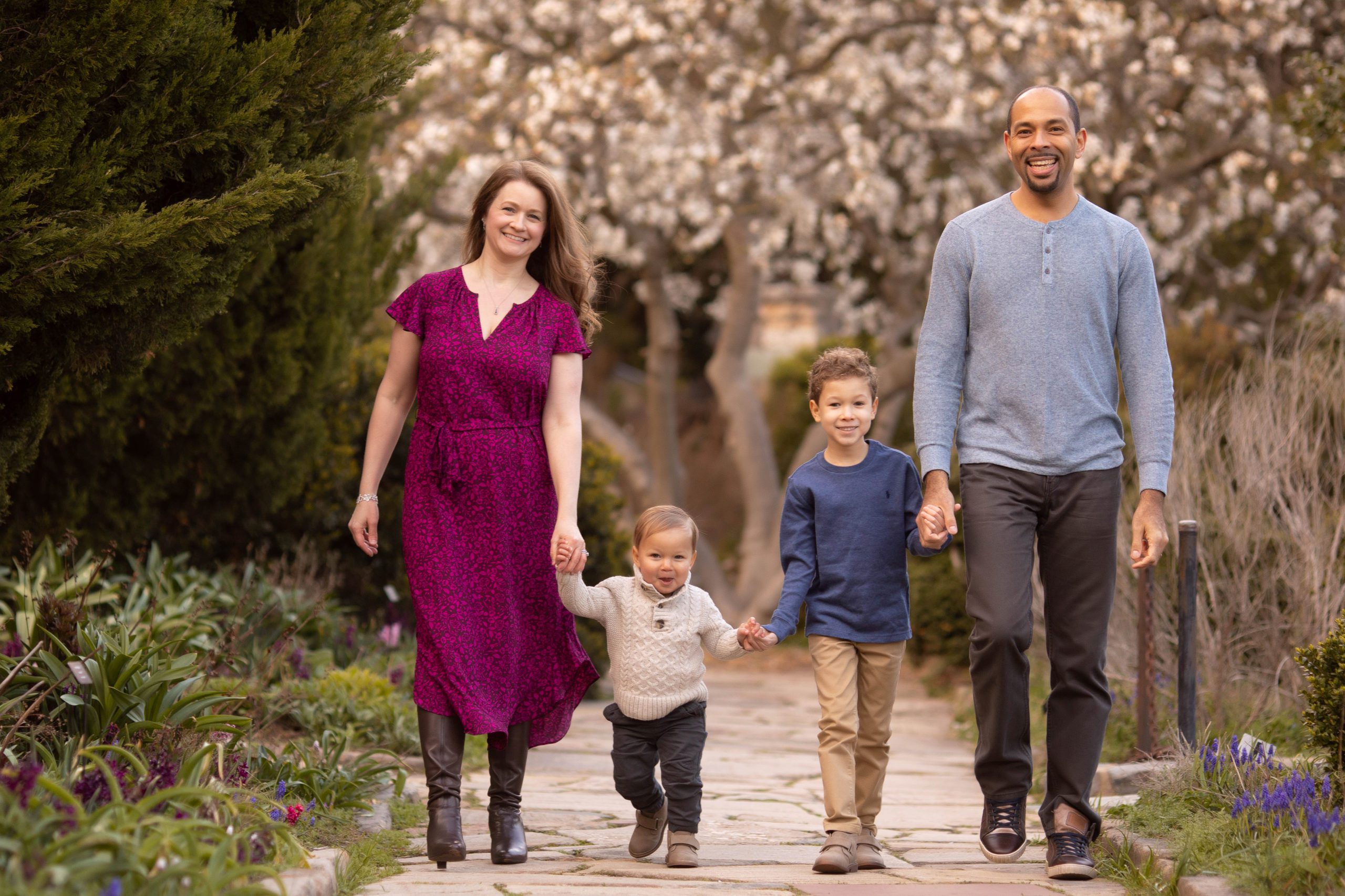 A family holding hands and walking in soft natural light during a lifestyle session by Marian Lozano, Northern Virginia family and newborn photographer.